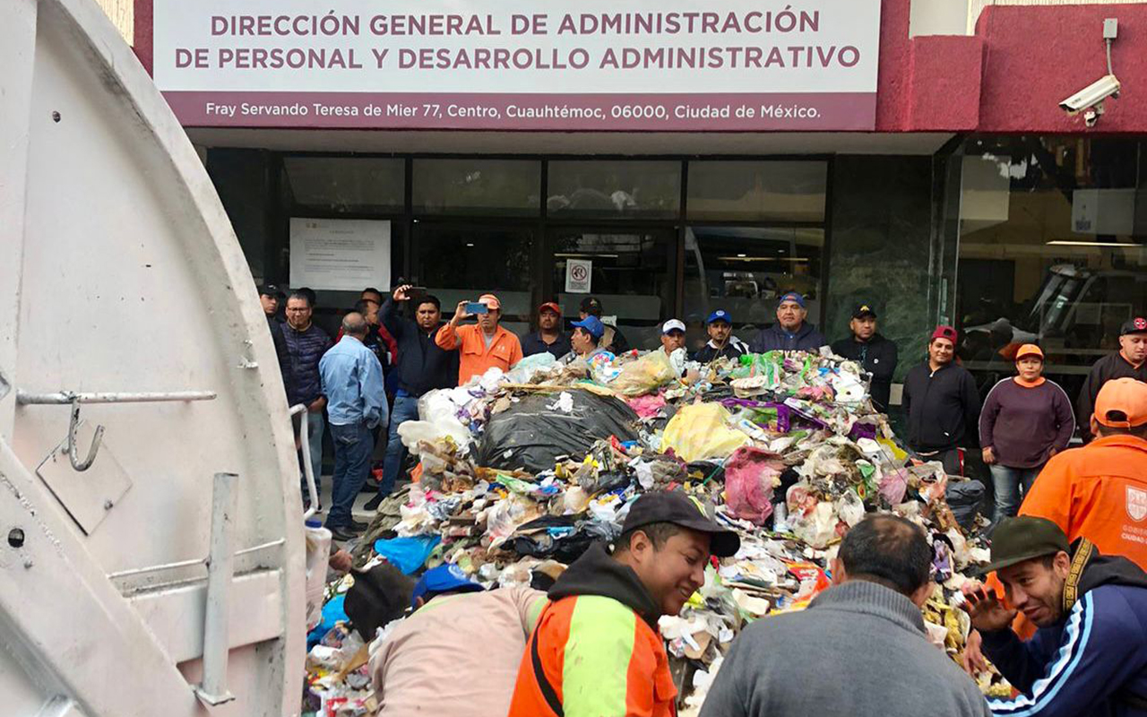 Trabajadores de limpia exigen pago de bono; tiran basura afuera de oficinas
