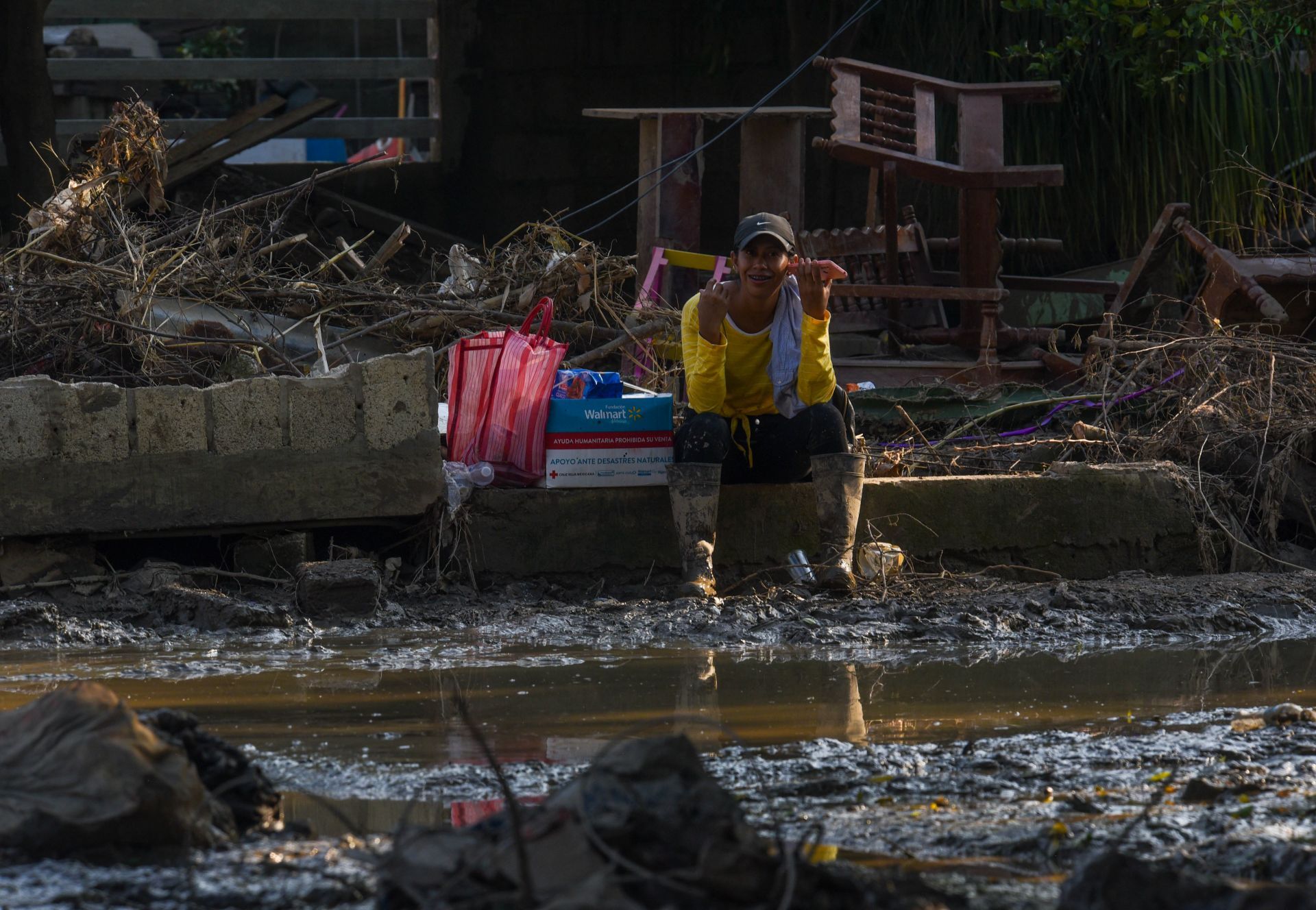 ÁLAMO, VERACRUZ, 18OCTUBRE2025.- Una mujer sentada entre el lodo y escombros habló por celular en el municipio de Álamo, en donde continúan los trabajos de limpieza en sus comunidades, las cuales se vieron afectadas por las lluvias. FOTO: CRISANTA ESPINOSA AGUILAR/CUARTOSCURO.COM